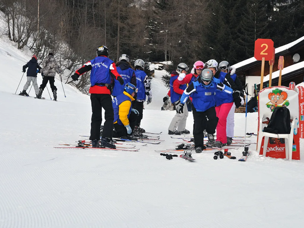 Skigruppe sammelt sich auf dem Übungshang neben einer Pistentafel.